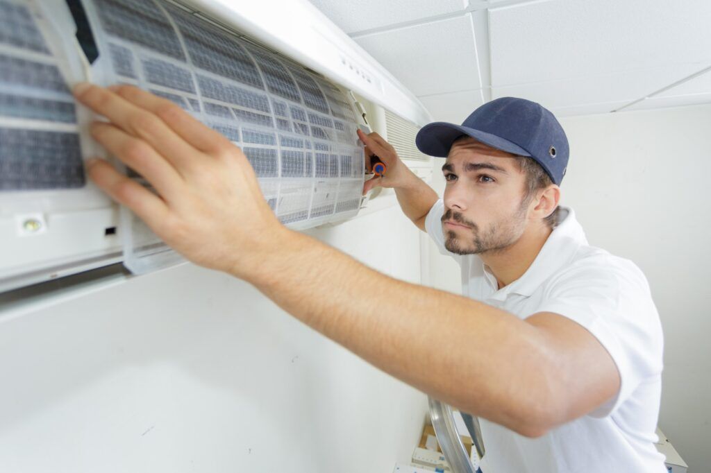 portrait-of-mid-adult-male-technician-repairing-air-conditioner